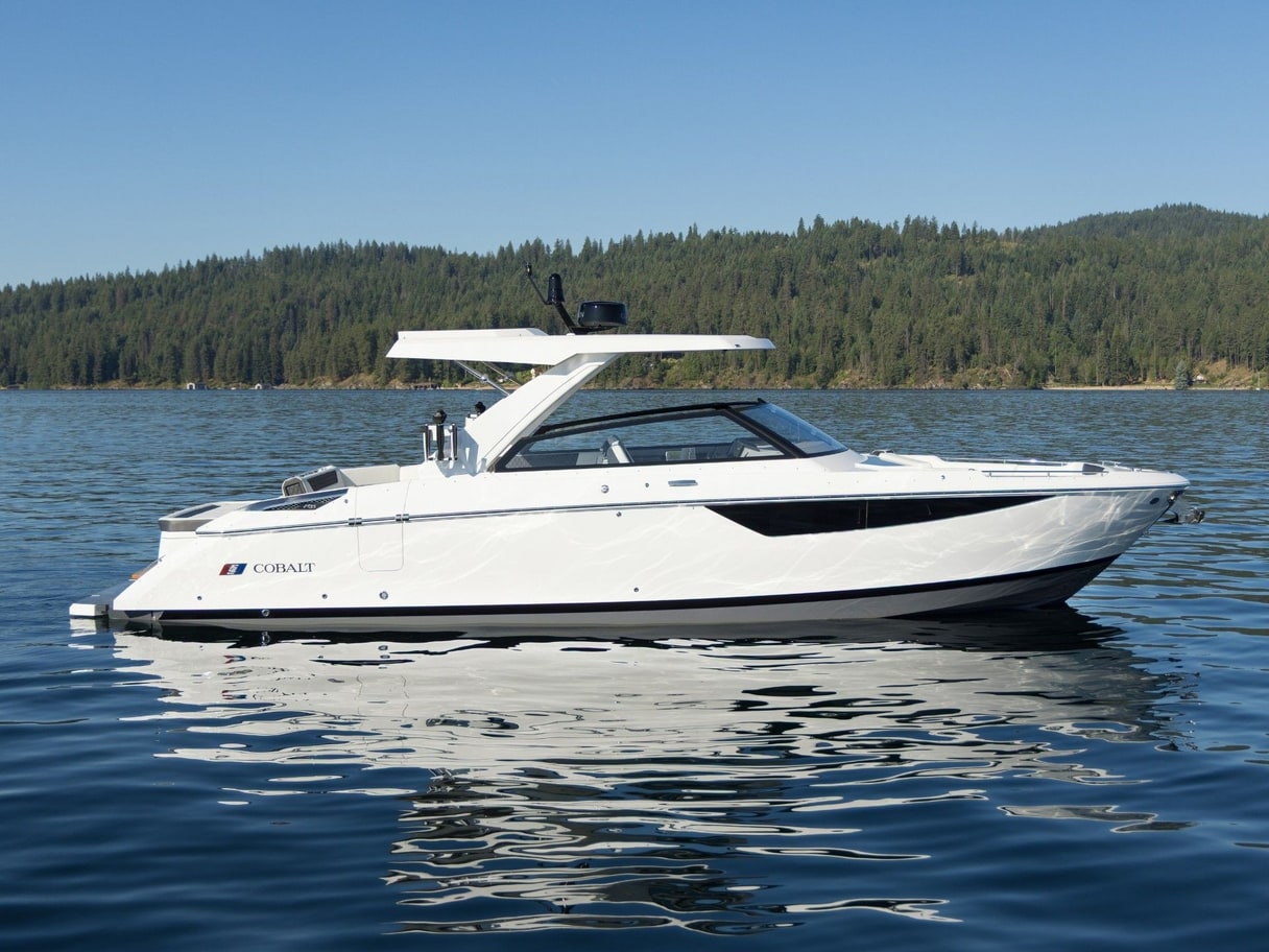 A white Caymas 28 HB center console on its trailer in a dealer lot, with palms and other boats behind it.